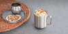 A stainless Steel Ember Mug is filled with vegan whipped cream and topped with pecans. It sits next to a woven mat that has a saucer of pecans and additional cream.