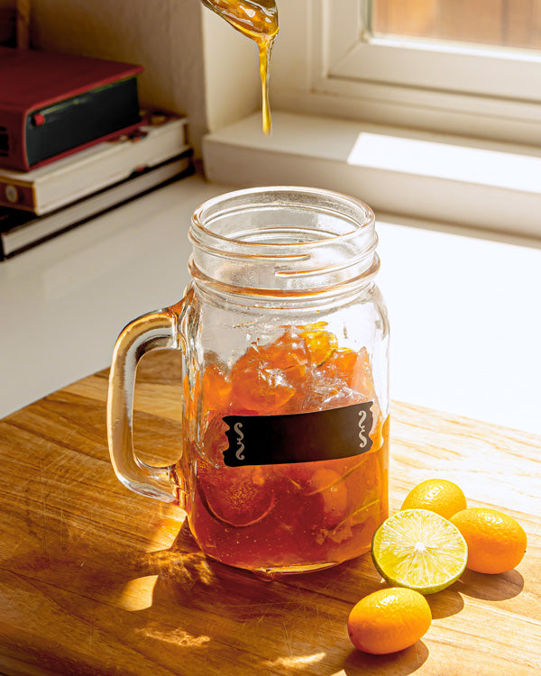 A jar of freshly made kumquat concentrate sits next to a sunny window.